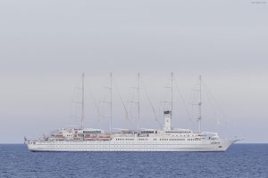 Le voilier Club Med 2 de profil en pleine mer, coque blanche et cinq mâts aux voiles ferlées