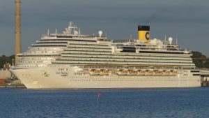 Le paquebot Costa Diadema, coque blanche et cheminée jaune au logo C de Costa, naviguant de profil en quittant le port de Kiel
