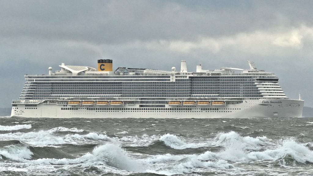 Le paquebot Costa Smeralda de Costa Croisières naviguant de profil sur une mer agitée, avec sa cheminée jaune frappée du C de la compagnie