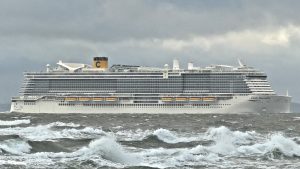 Le paquebot Costa Smeralda de Costa Croisières naviguant de profil sur une mer agitée, avec sa cheminée jaune frappée du C de la compagnie