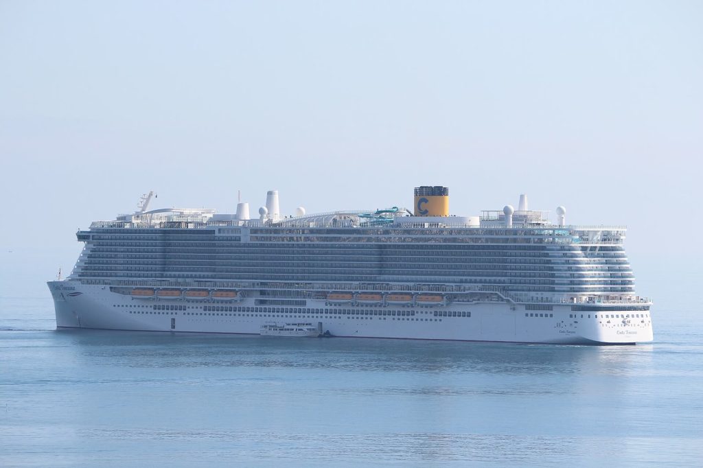 Le paquebot Costa Toscana de Costa Croisières vu de profil sur une mer calme, avec sa cheminée jaune frappée du C et les toboggans sur le pont supérieur