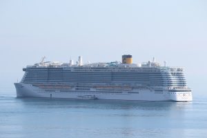 Le paquebot Costa Toscana de Costa Croisières vu de profil sur une mer calme, avec sa cheminée jaune frappée du C et les toboggans sur le pont supérieur