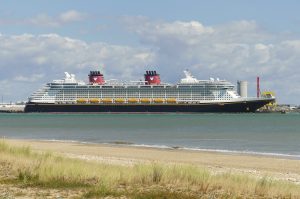 Le paquebot Disney Dream, coque bleu nuit et cheminées rouges ornées de Mickey, à quai à La Rochelle, vu depuis une plage de l'île de Ré