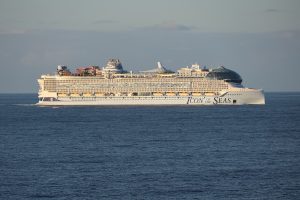 Le paquebot Icon of the Seas de Royal Caribbean naviguant de profil en pleine mer, avec le parc aquatique à l'arrière et le dôme vitré à l'avant