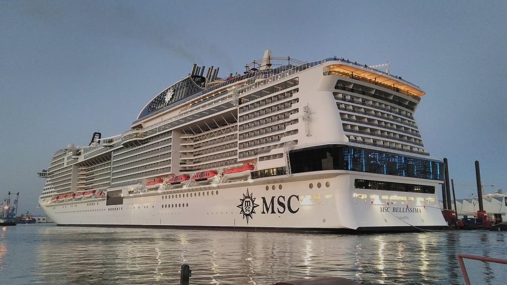 Le paquebot MSC Bellissima à quai dans le bassin de Penhoët à Saint-Nazaire, vu de trois quarts arrière au crépuscule, avec ses ponts de balcons et le logo MSC sur la coque