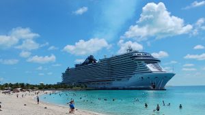 Le paquebot MSC Seashore à quai devant la plage de sable blanc d'Ocean Cay, aux Bahamas, avec des baigneurs dans l'eau turquoise