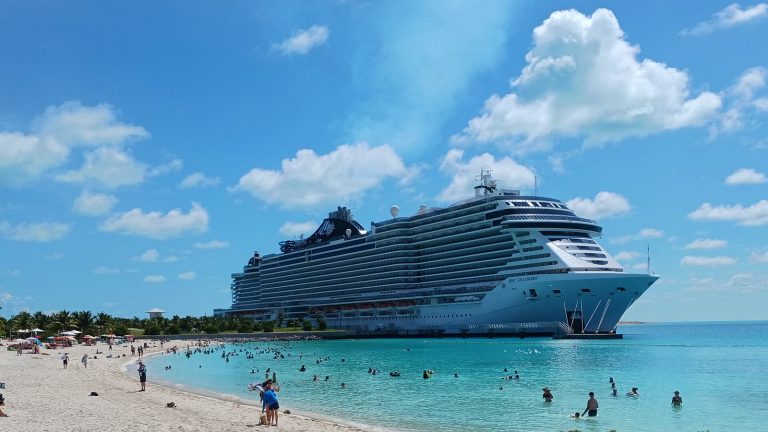 Le paquebot MSC Seashore à quai devant la plage de sable blanc d'Ocean Cay, aux Bahamas, avec des baigneurs dans l'eau turquoise