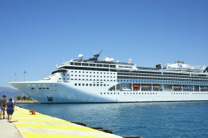 Le paquebot MSC Opera, coque blanche et cheminée sombre, amarré le long d'un quai peint en jaune, avec des promeneurs au premier plan
