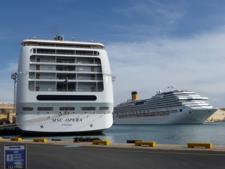La poupe du paquebot MSC Opera amarré au premier plan, et le Costa Pacifica à cheminée jaune qui entre dans le port de La Valette, à Malte