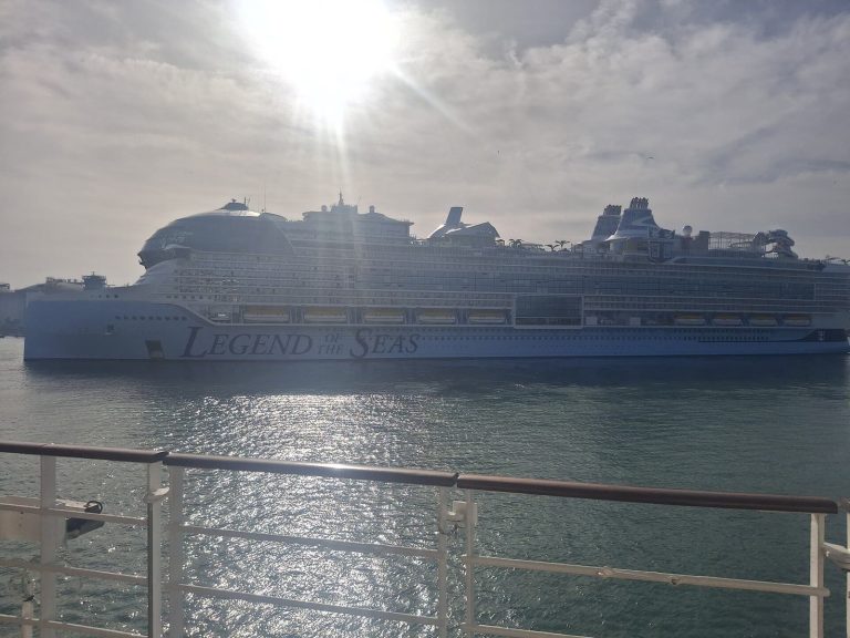 Le paquebot Legend of the Seas de Royal Caribbean vu de profil depuis le pont d'un autre navire, dans le port de Barcelone, avec son dôme vitré à l'avant et ses toboggans à l'arrière