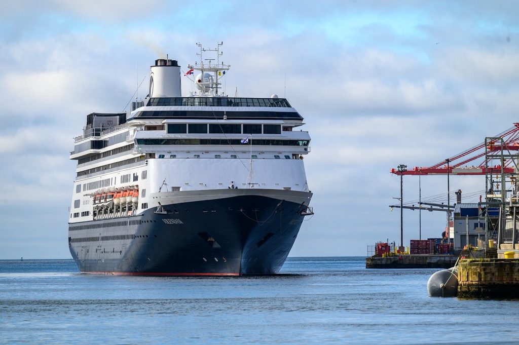 Le paquebot Volendam de Holland America Line vu de face, coque bleu nuit et superstructure blanche, arrivant dans le port de Halifax près de grues portuaires